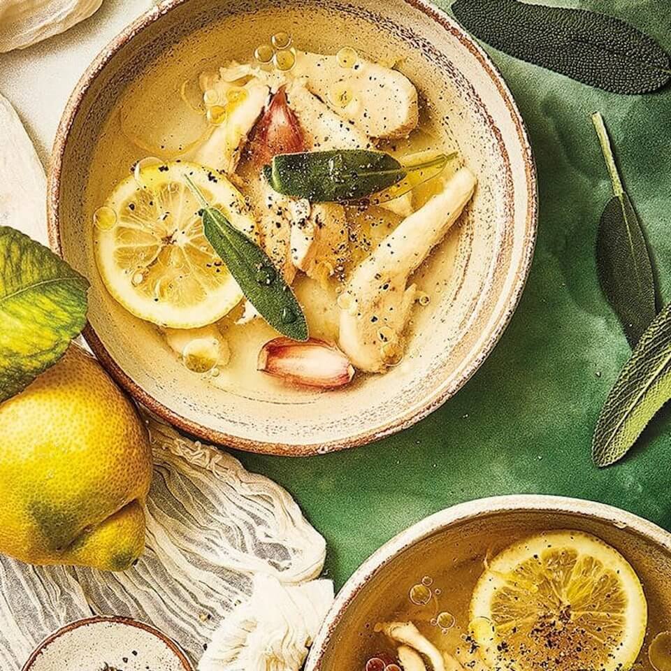 Bowls of broth with chicken and lemons