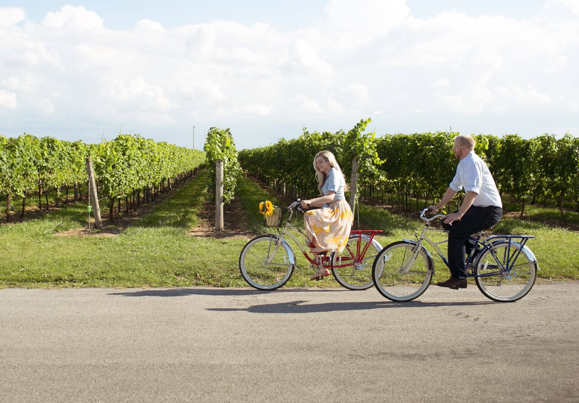 A young woman rides a bicycle with a vineyard in the background