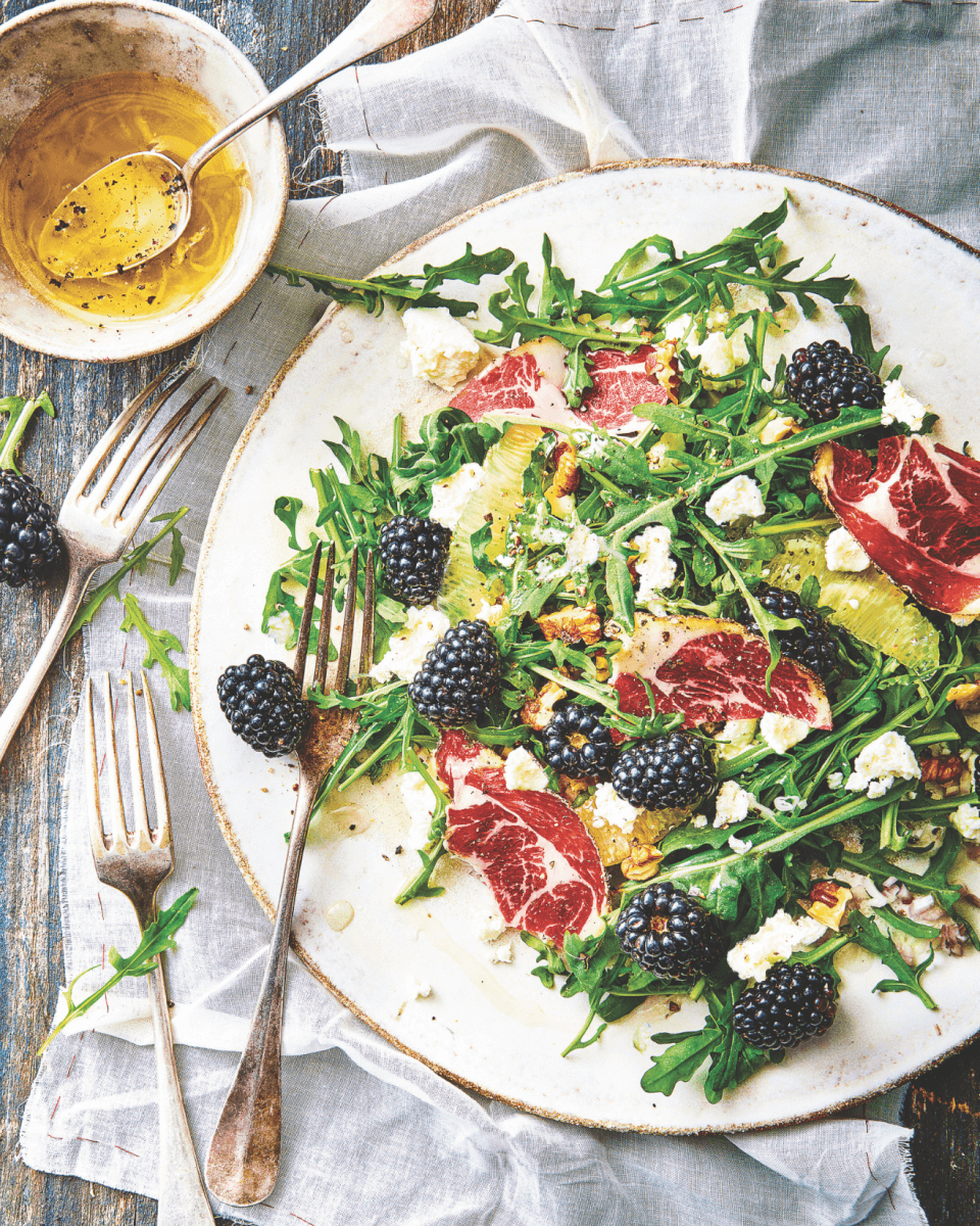 plate with arugula salad and blackberries