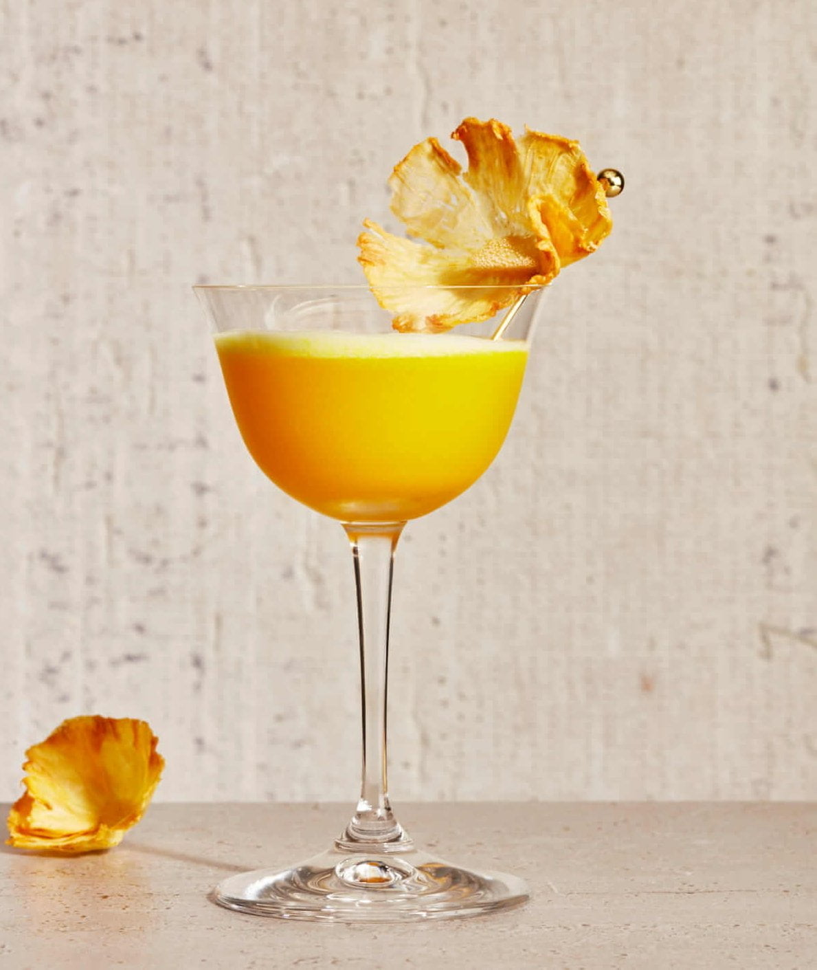 A bright orange cocktail with a pineapple garnish.