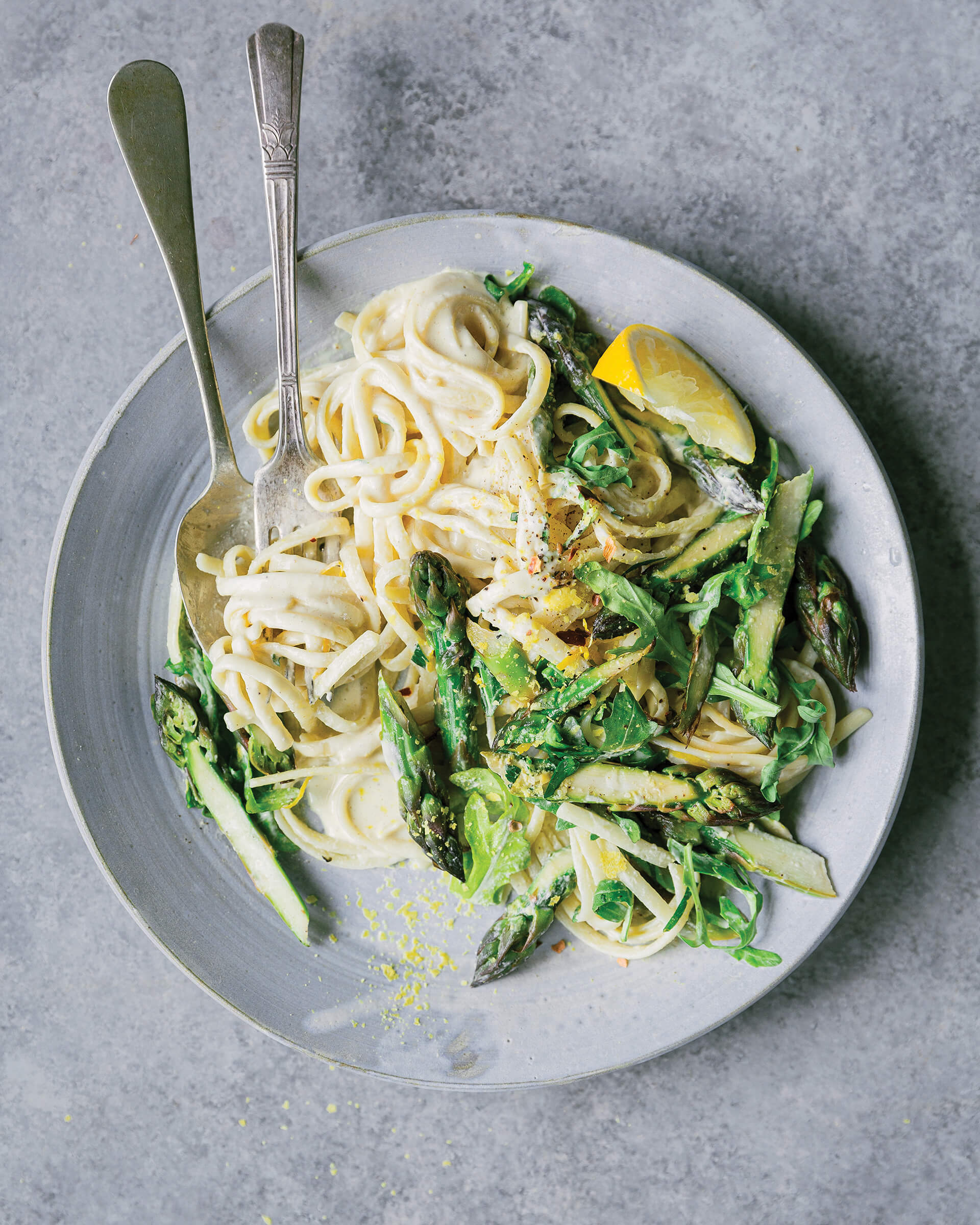 A plate of pasta and asparagus with cutlery.