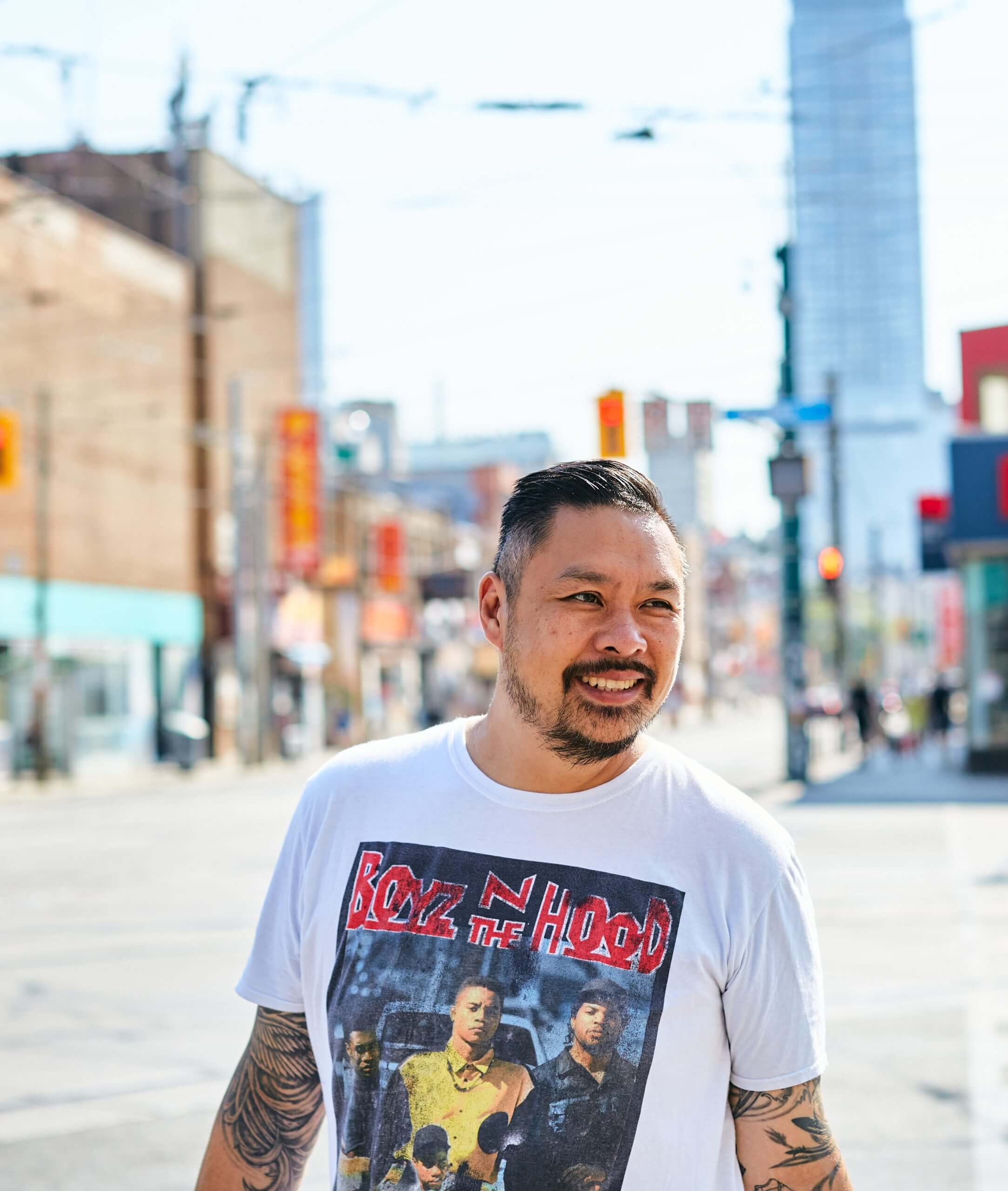 Trevor Lui, wearing a "Boyz N The Hood" Tshirt, smiles on a Toronto street.