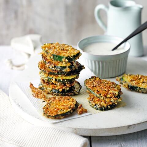 Stacks of crispy courgette with white aioli dip on the side.