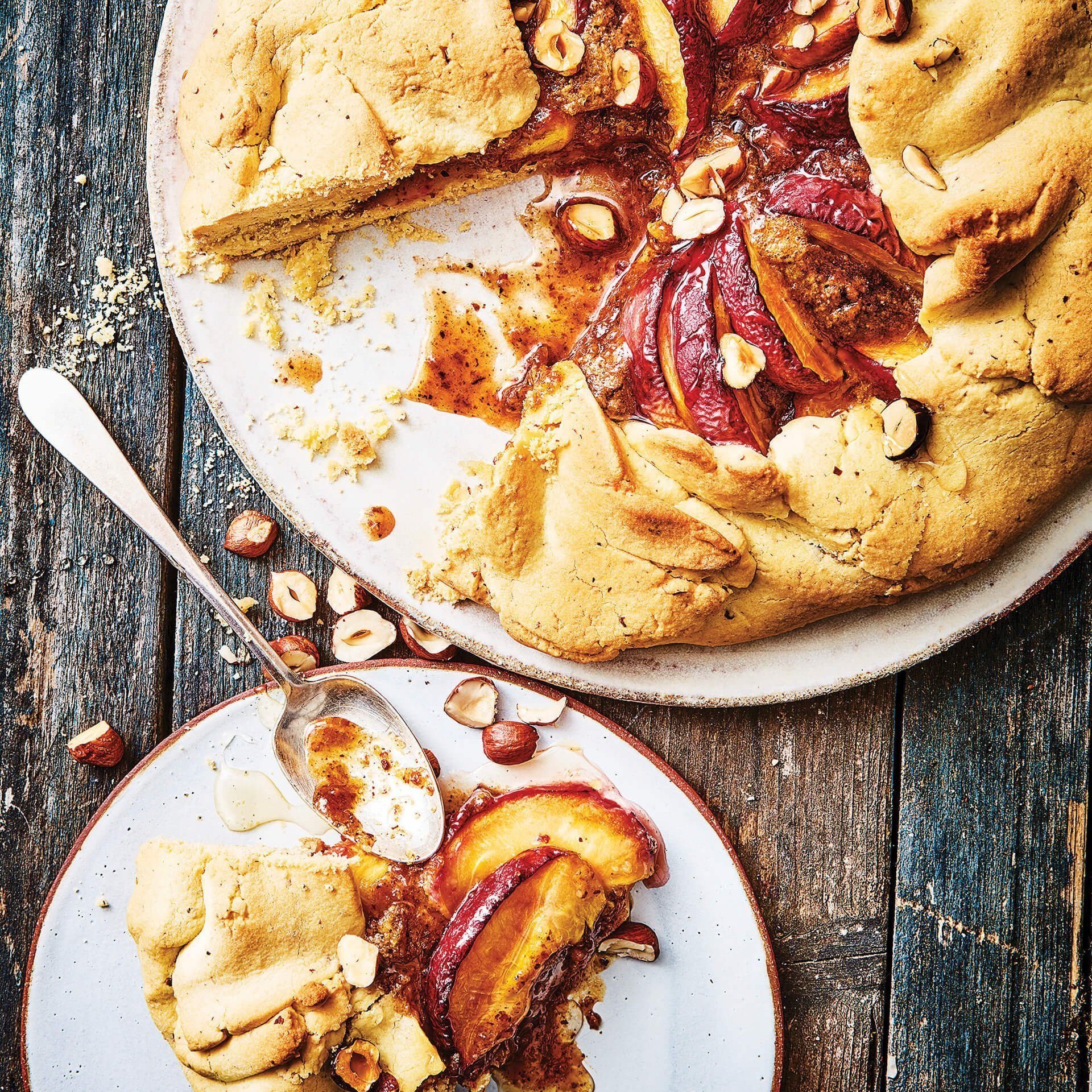 A peach tart with one slice on a plate next to it.