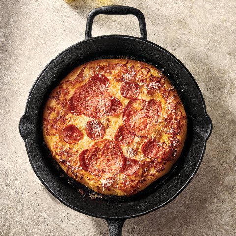 A black cast iron pan with a small pizza in it
