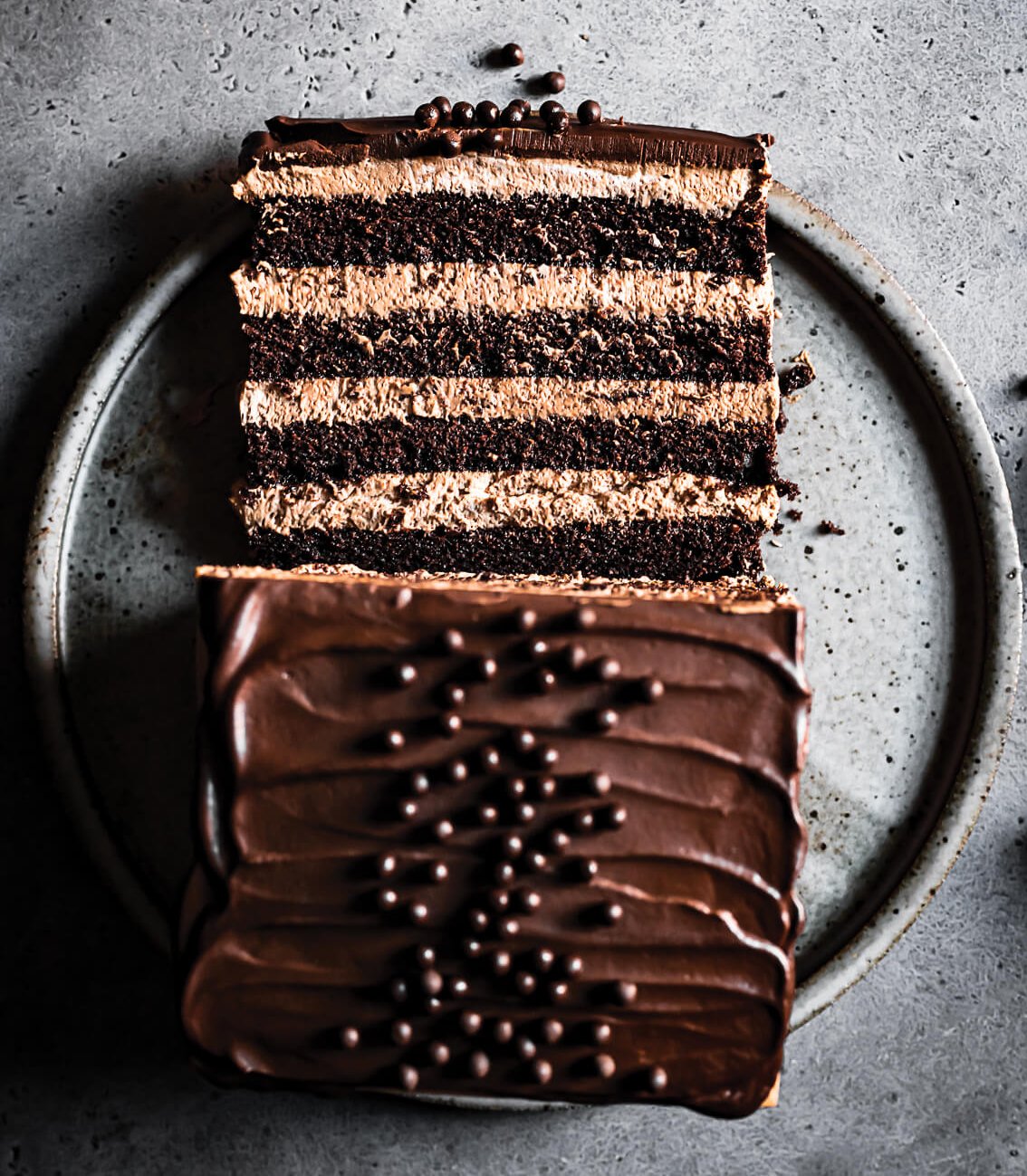 A layered chocolate cake on a grey plate