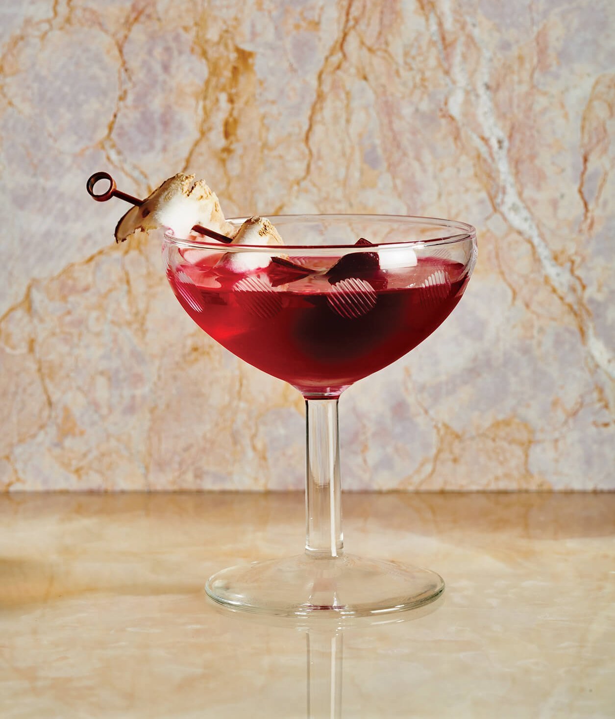 A dark red cocktail on a marble surface