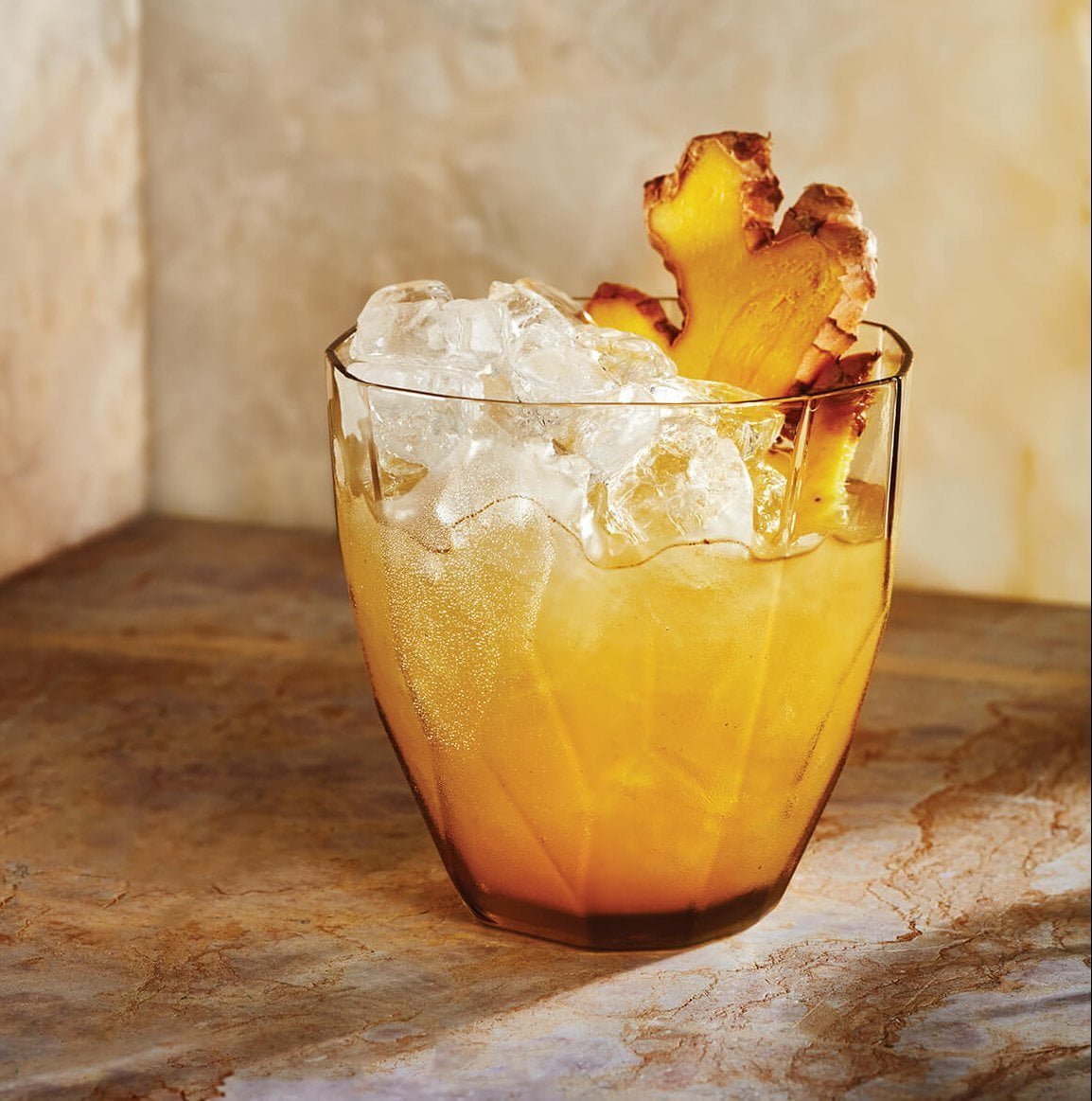 A bright orange drink with ginger garnish