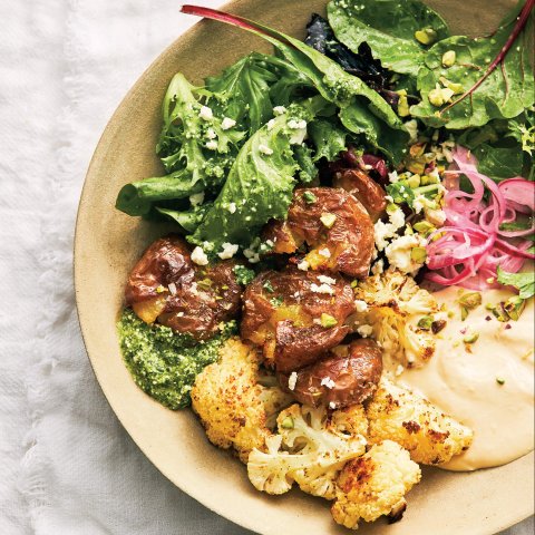 A tan bowl with vegetables and salad