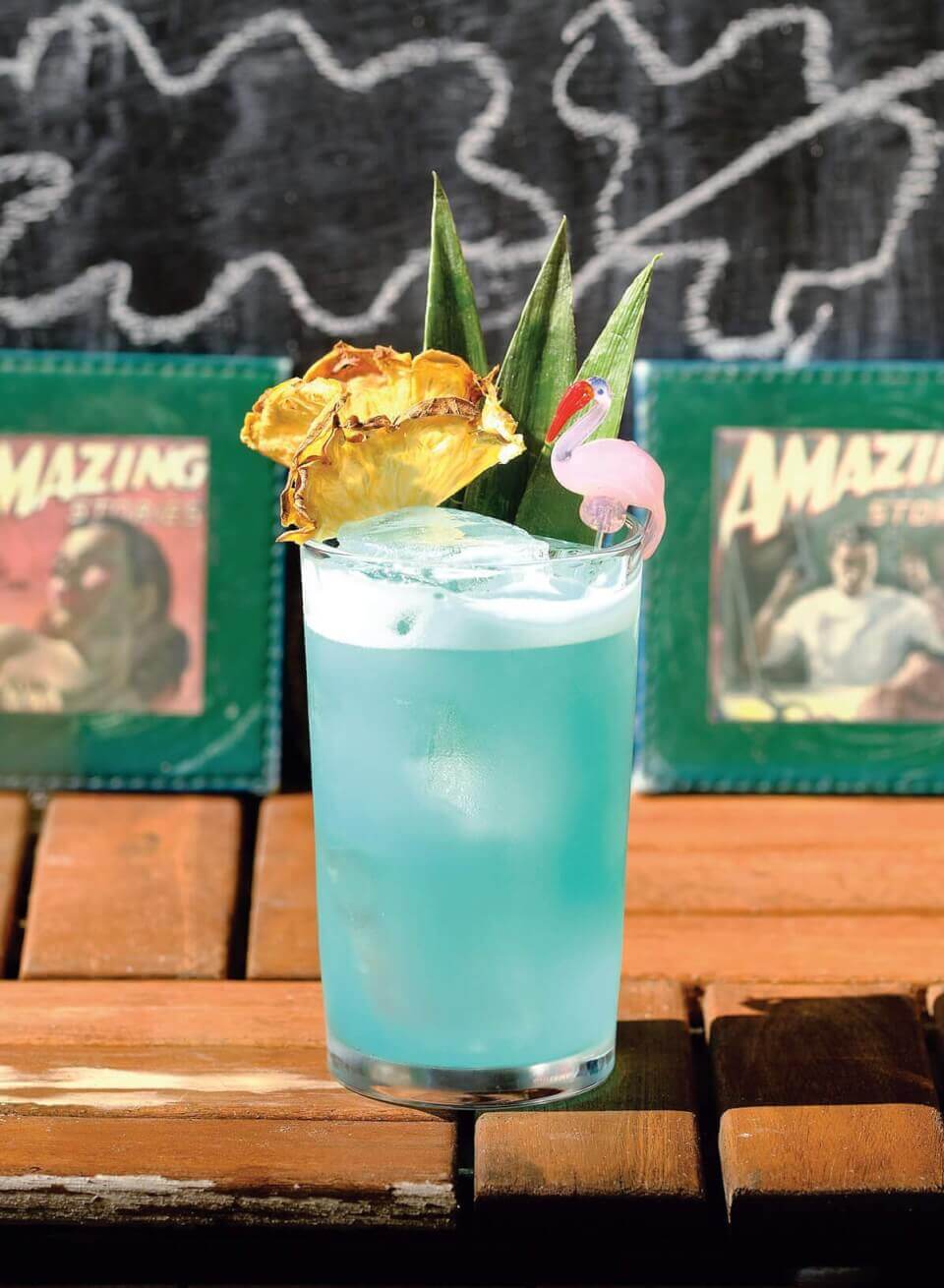 A bright blue cocktail on a wooden table