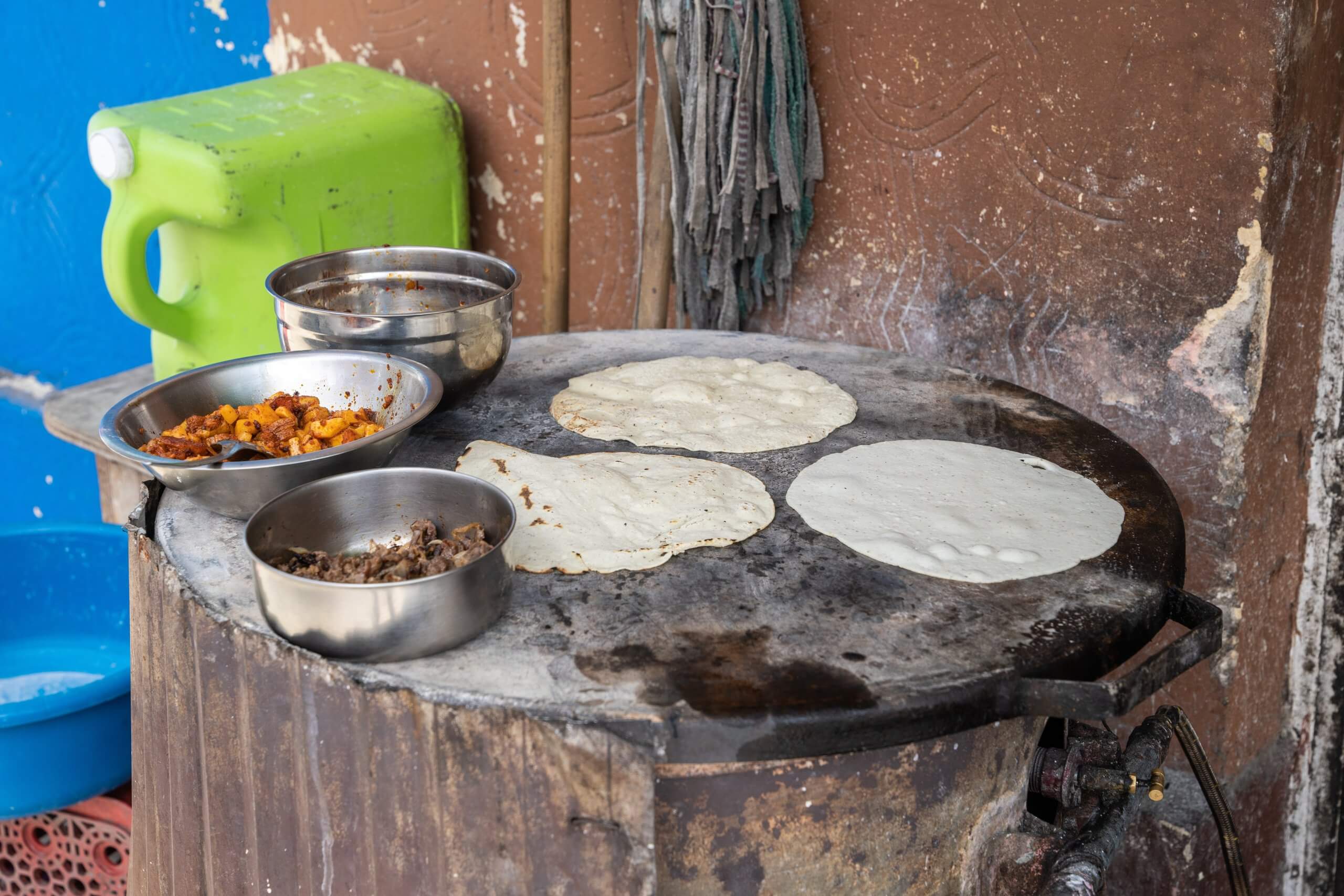 A flat griddle with three tortillas and bowls of seasonings