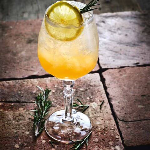 A cocktail with a lemon wheel and thyme sprig