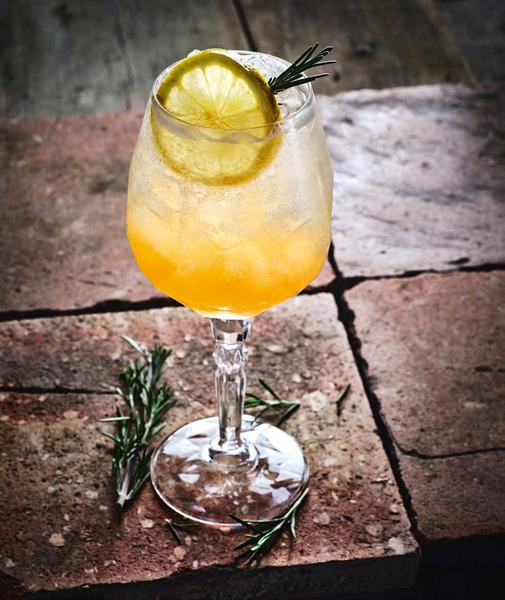 A cocktail with a lemon wheel and thyme sprig
