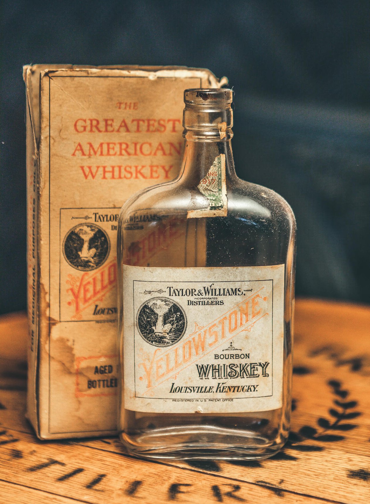 An old bottle of whiskey with a book behind it
