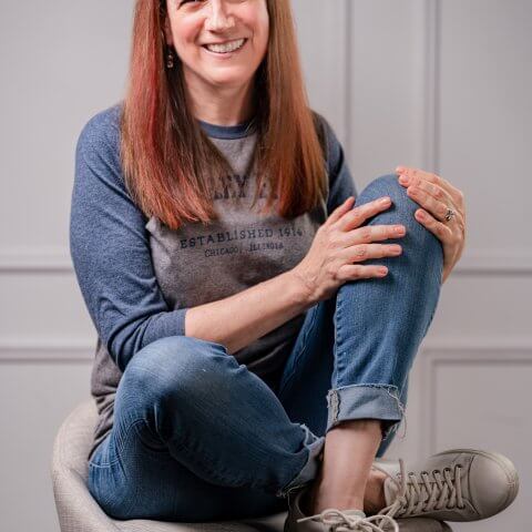 A woman in jeans and a t-shirt sitting on a stool