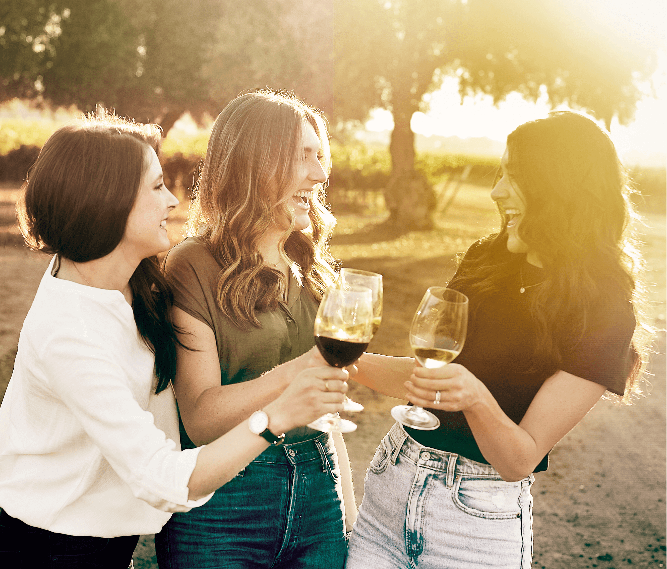 Three women with wine glasses laugh together