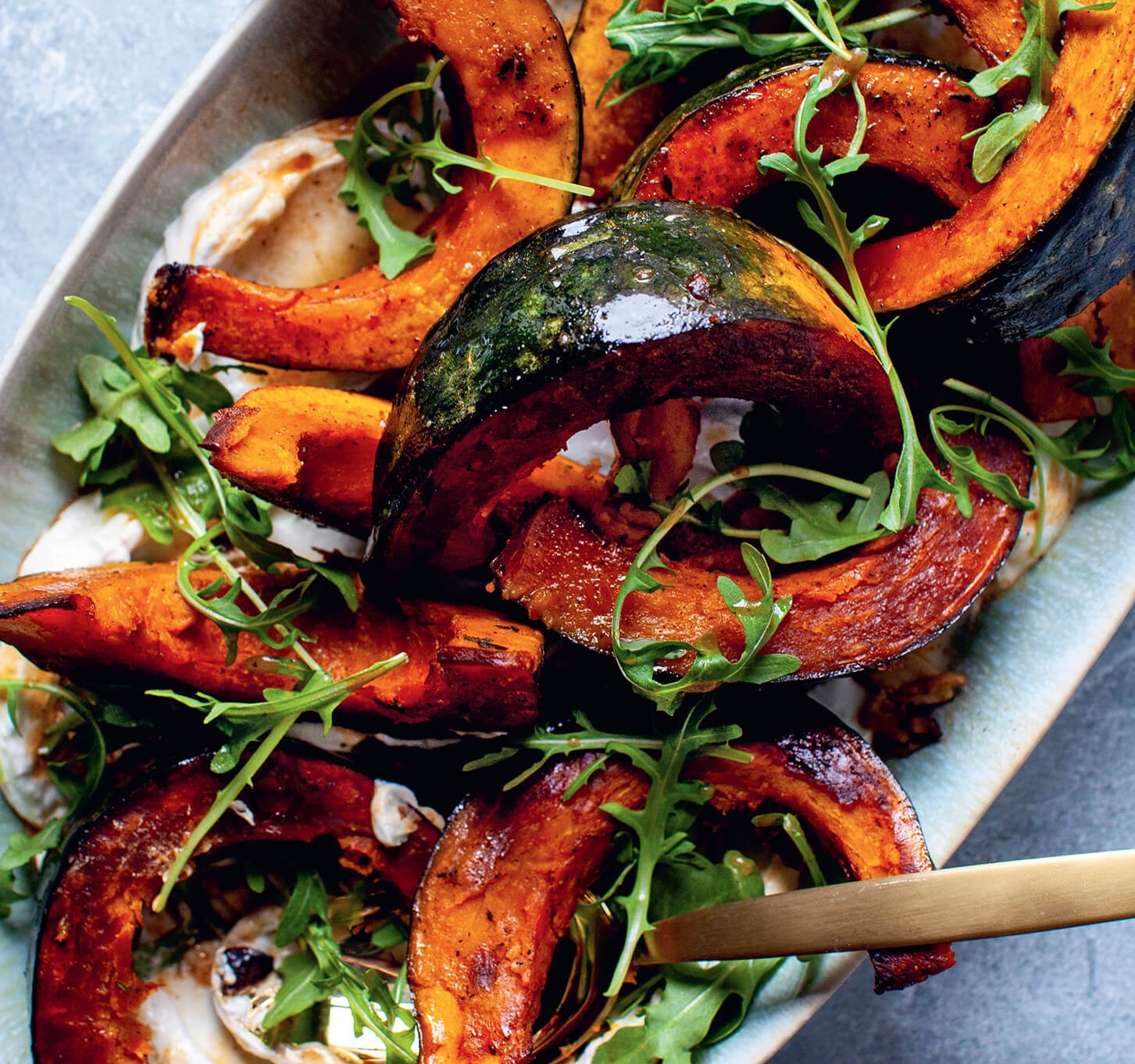 A closeup of squash wedges with arugula and yogurt