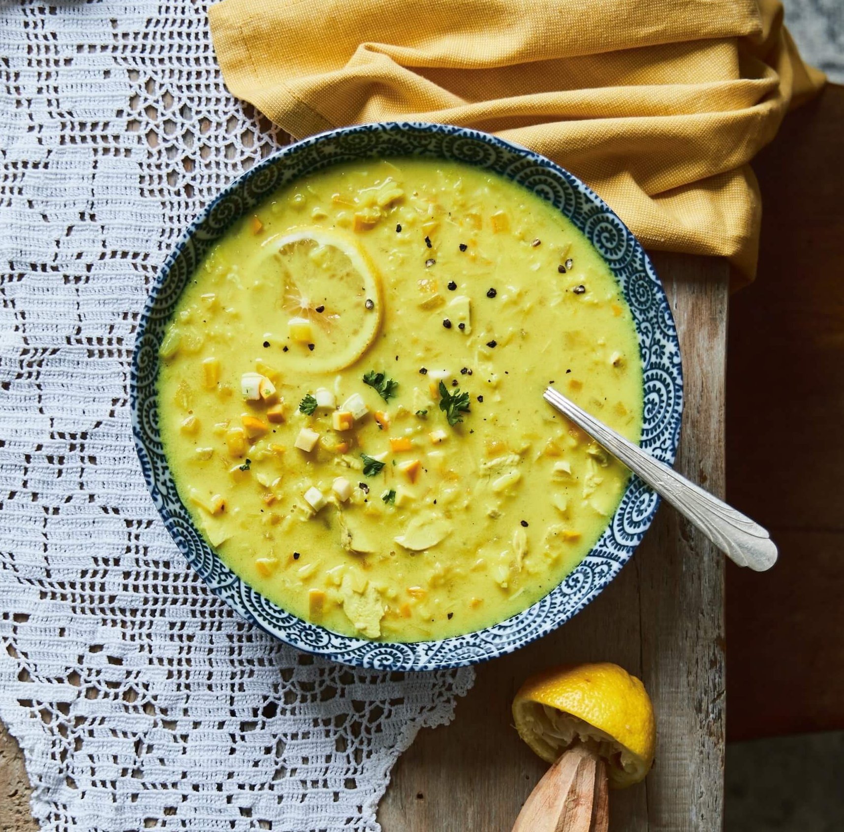 A bowl of yellow soup on a doily