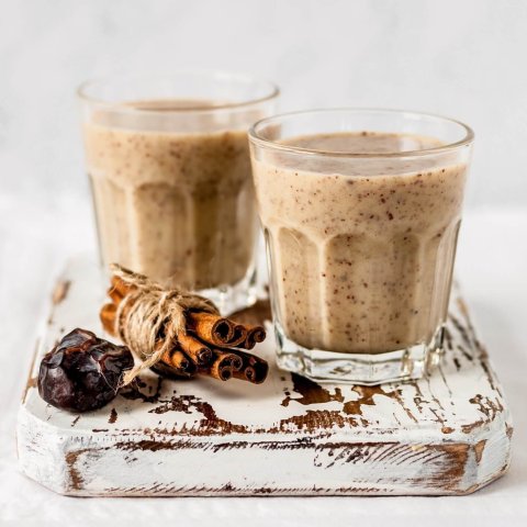 Two glasses of almond smoothie sitting on board