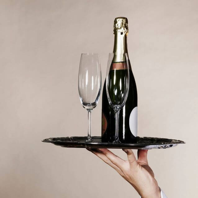 A tray with champagne and two flutes is held up