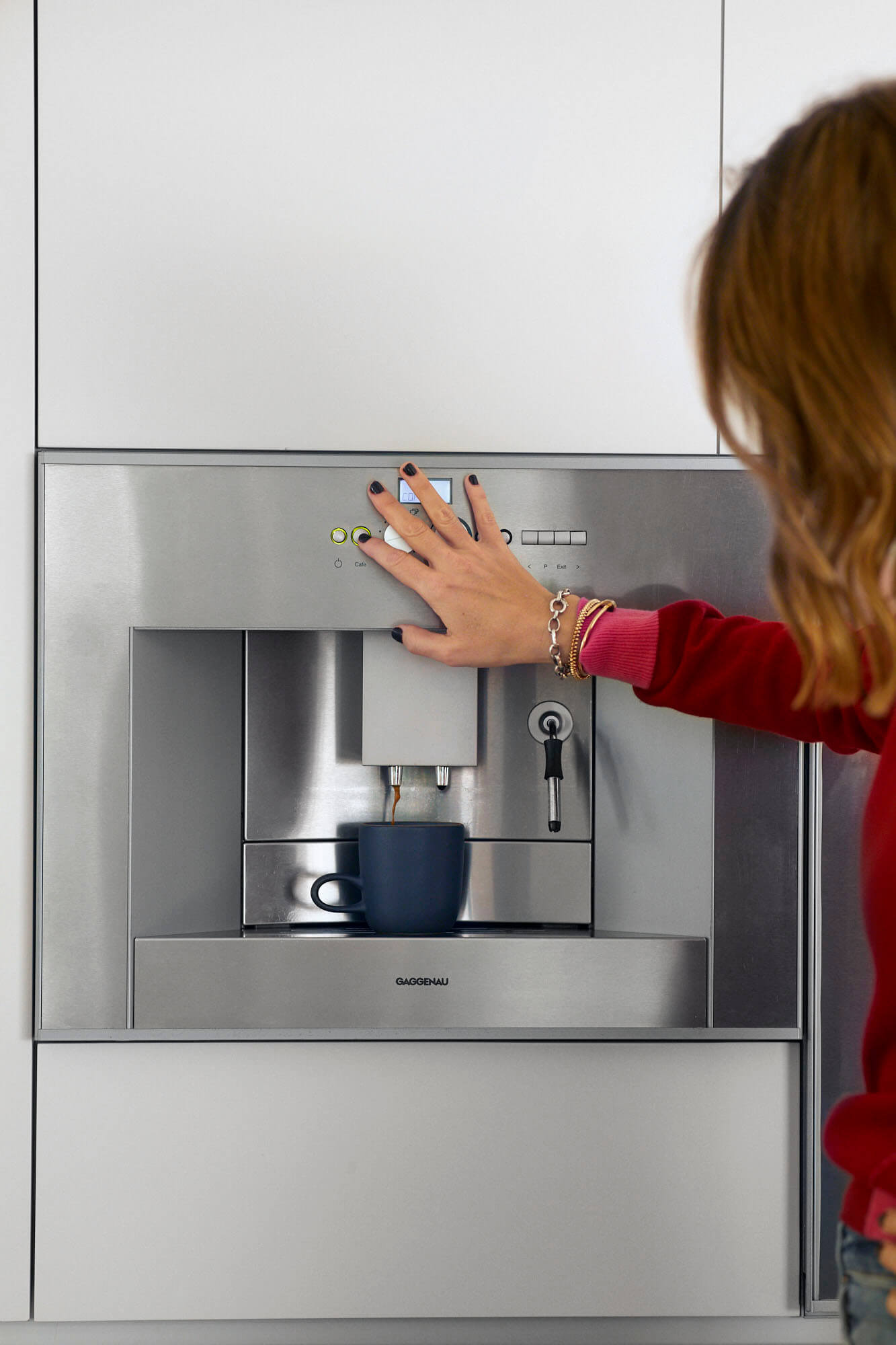A woman uses a wall unit espresso machine