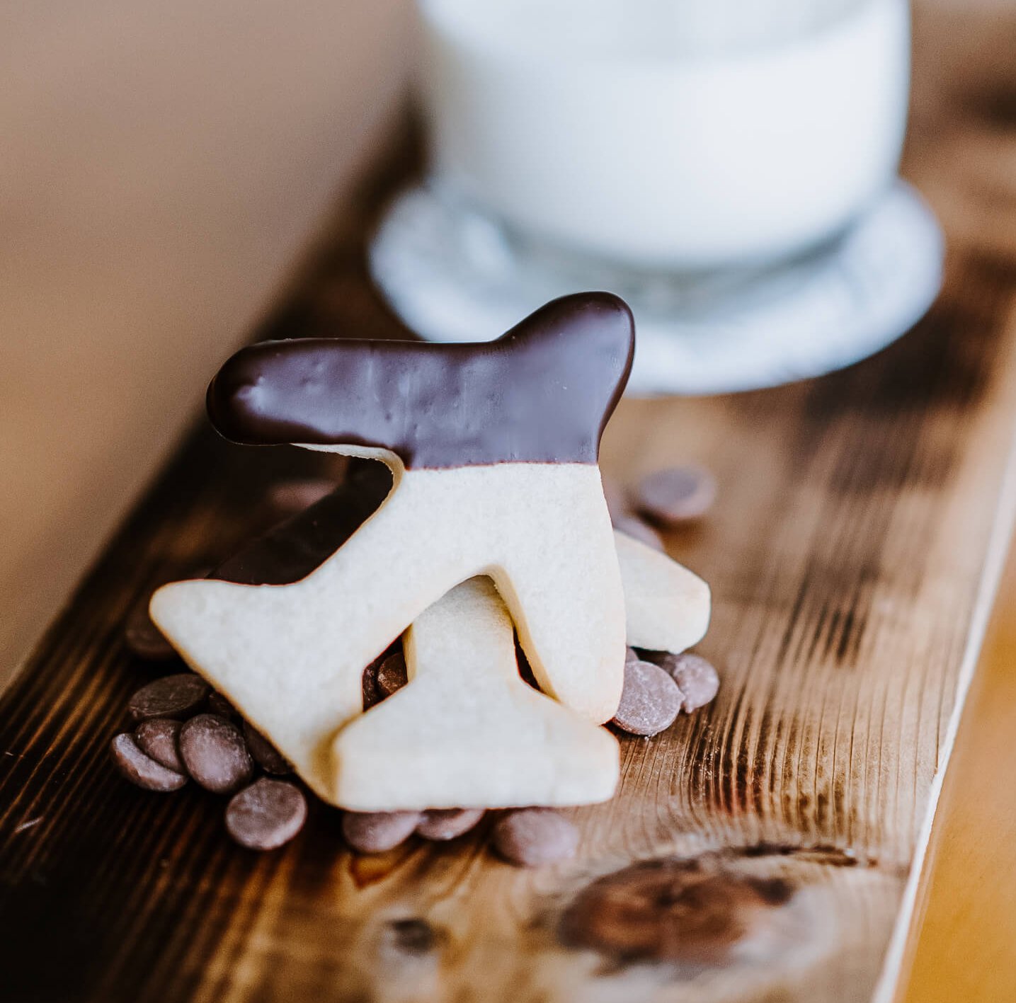 A board with a glass of milk and airplane-shaped cookies dipped in chocolate.