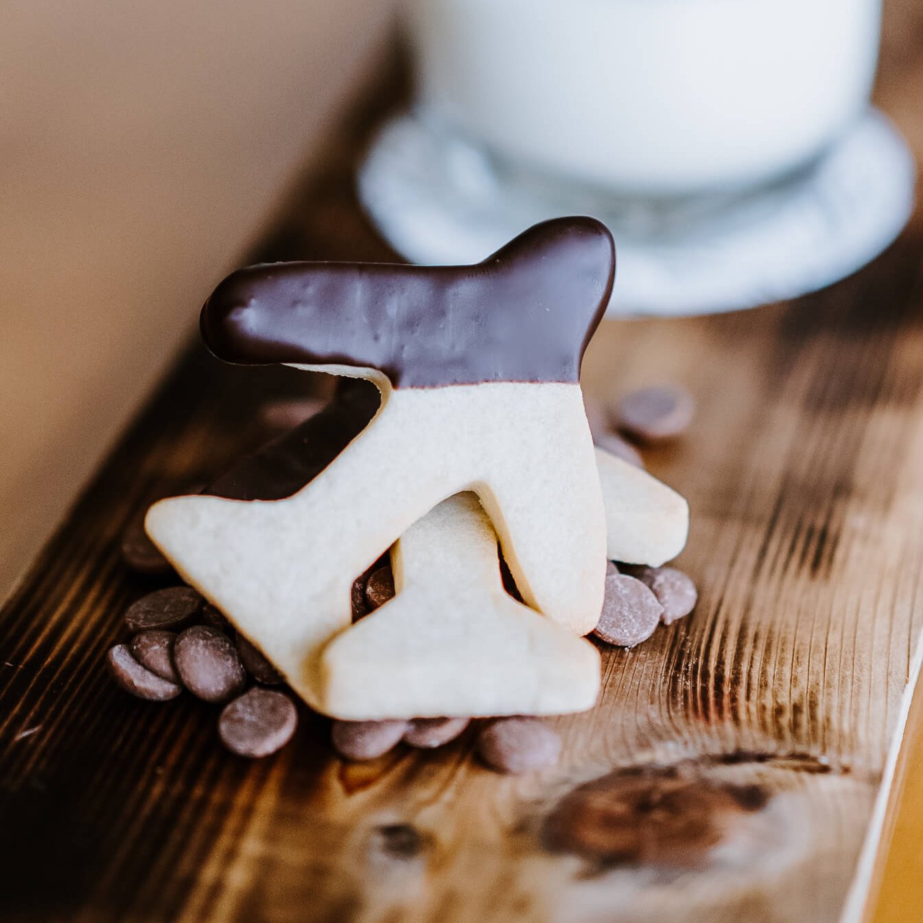 A board with a glass of milk and airplane-shaped cookies dipped in chocolate.