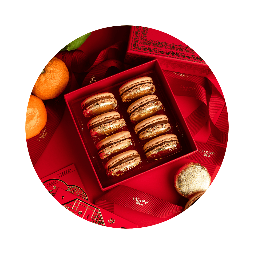 A red box with macarons covered in gold flakes in a circle-shaped frame.