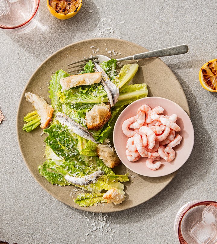 A caesar salad with shrimp on a tabletop.