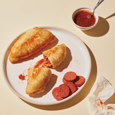 A dish with pizza pockets and sauce on the side.