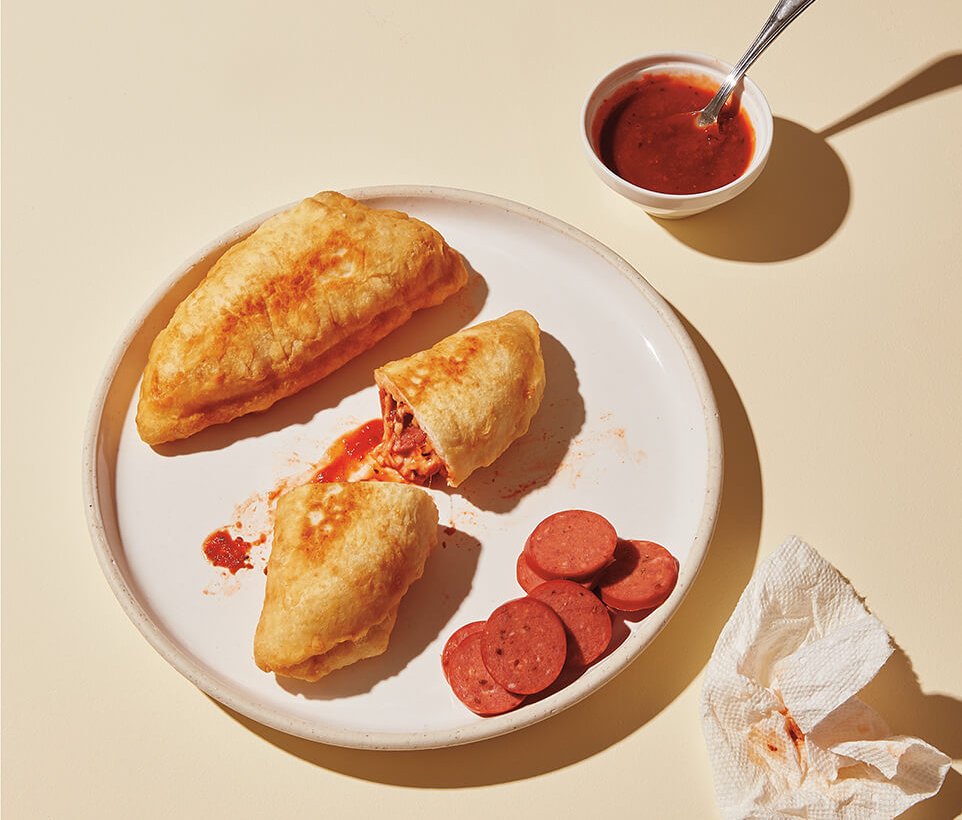 A dish with pizza pockets and sauce on the side.