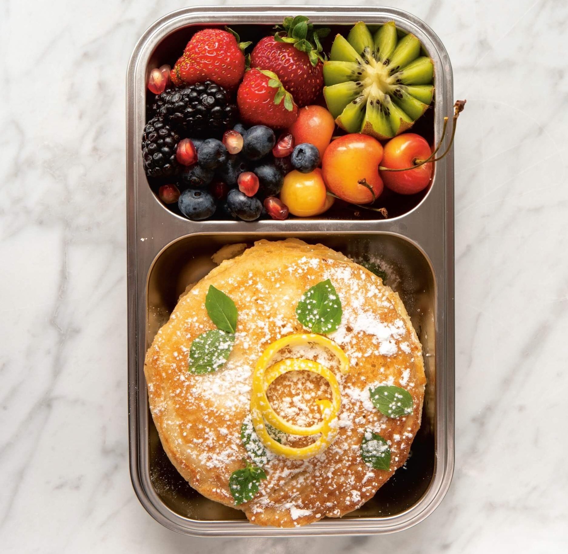 metal box with pancakes and fruit salad