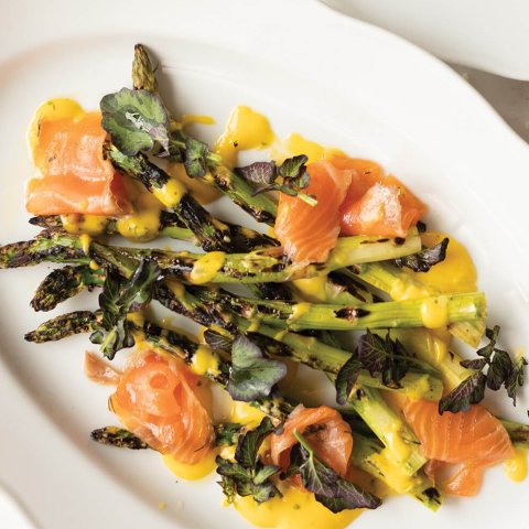 A white dish with asparagus, Bearnaise sauce and gravlax.