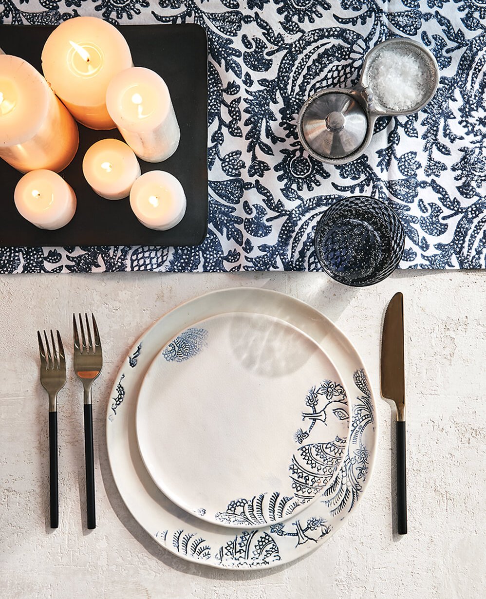 A blue and white table setting with clustered candles.