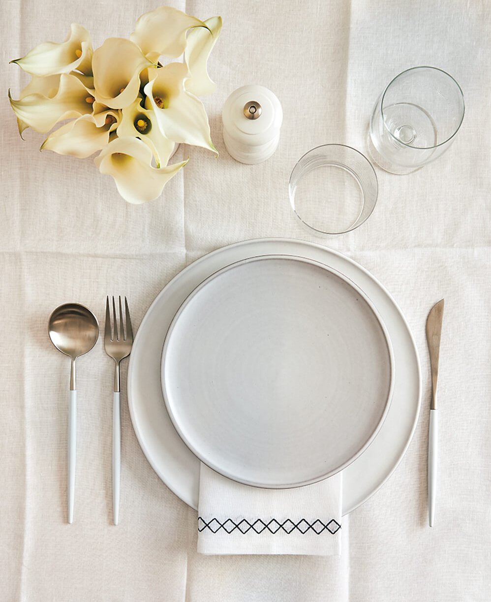 An all-white table setting with flowers.