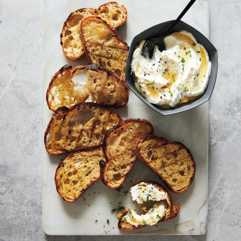 A stone surface with grilled bread and ricotta.