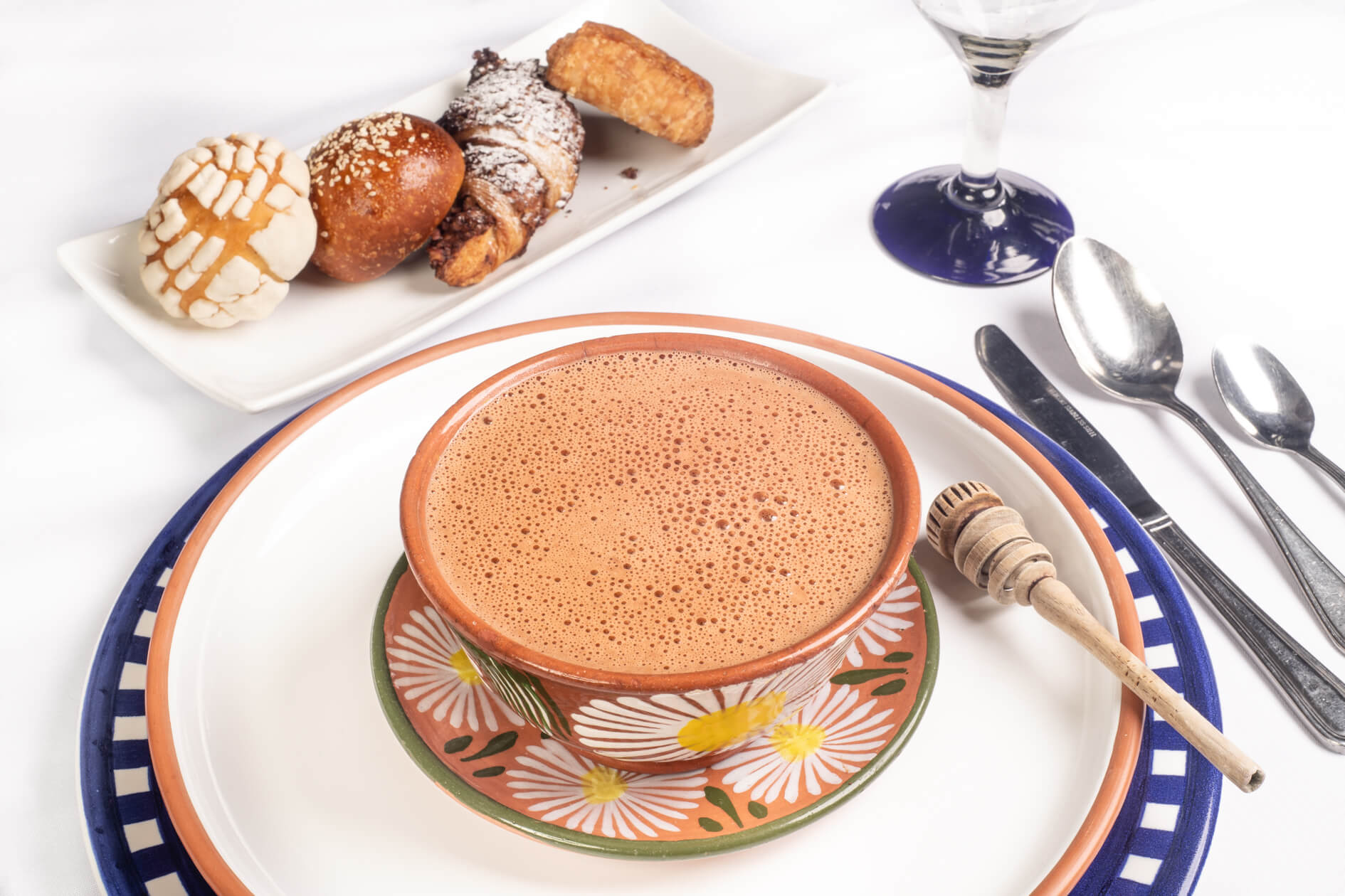 A mug of drinking chocolate in a patterned cup with desserts in the background.