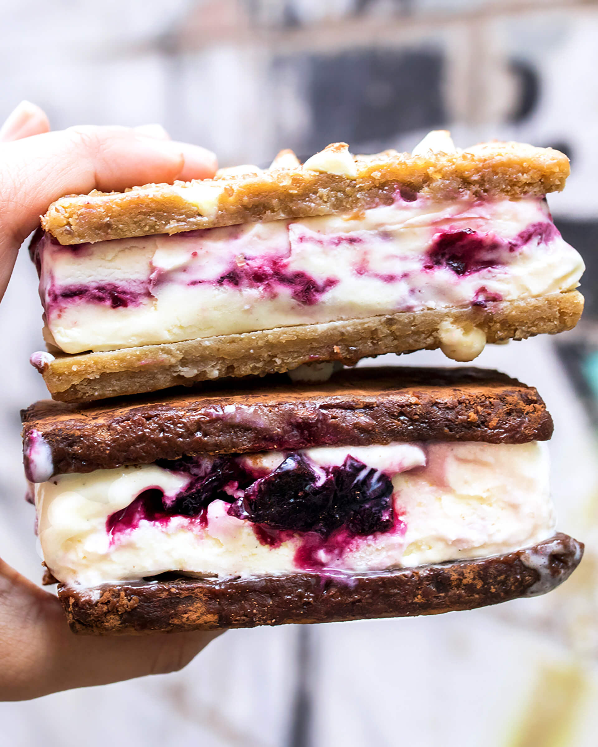A person's hand holding two ice cream sandwiches