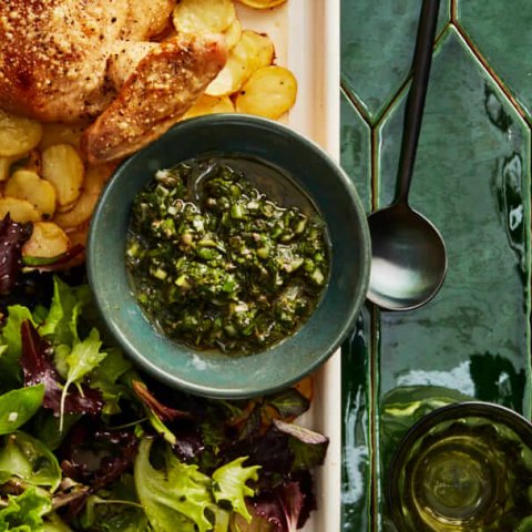 bowl of green salsa on tray with salad and chicken