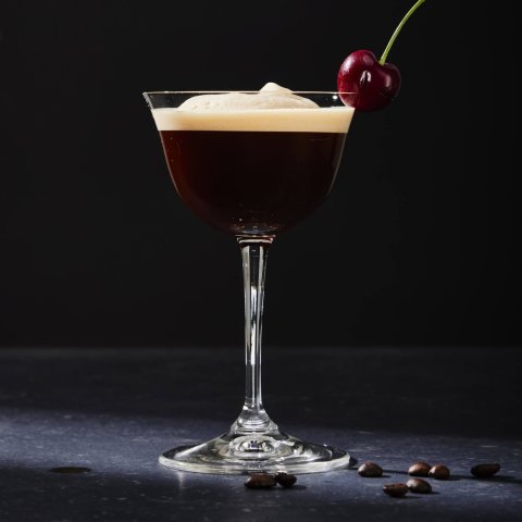 glass with coffee martini in it against black background