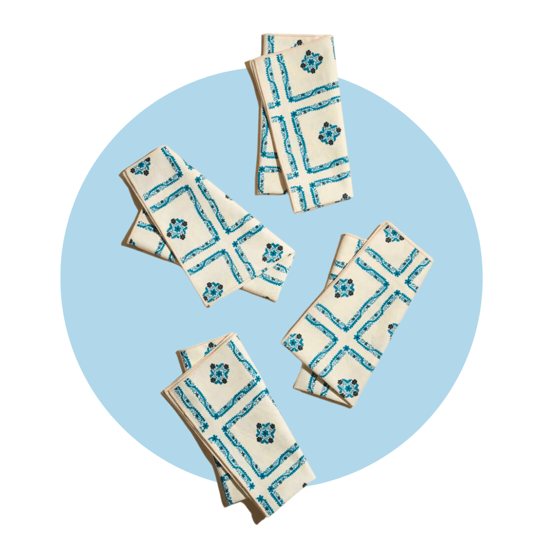 Four blue and white patterned cloth napkins on a light blue circle graphic.