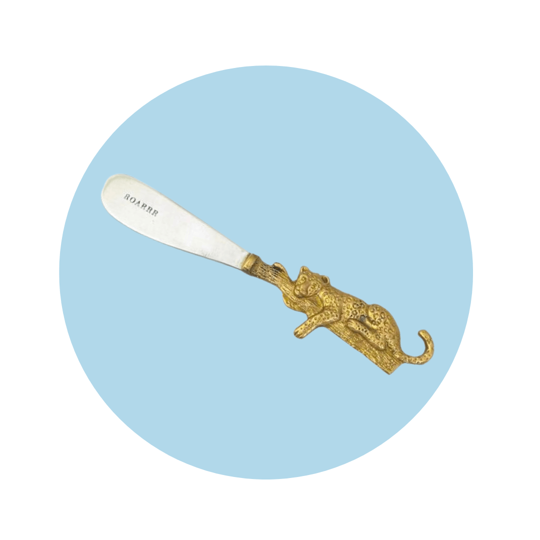 A butter knife with a leopard shaped handle on a light blue circle graphic
