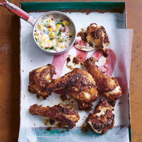 A tray with chicken wings and a side of creamed corn photographed from above