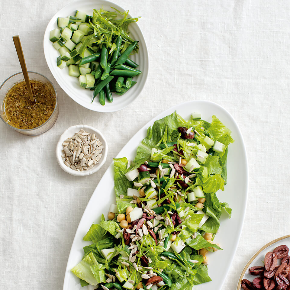 White dishes with salad and dressings on the side of a Kohlrabi saladphotographed from above.