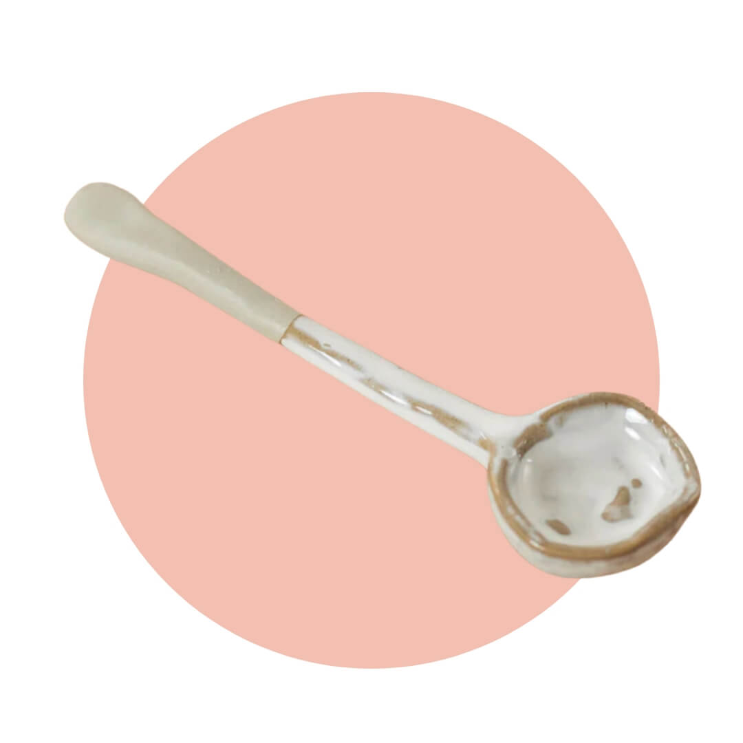 A ceramic spoon on a light pink circle graphic