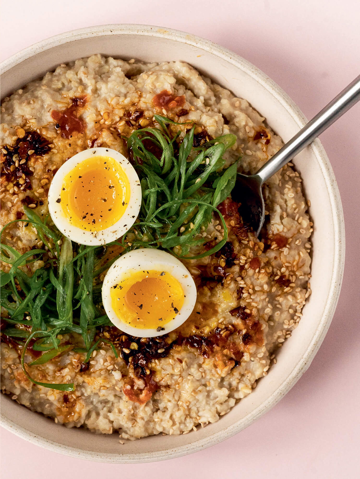 A bowl of oatmeal on a light pink background.
