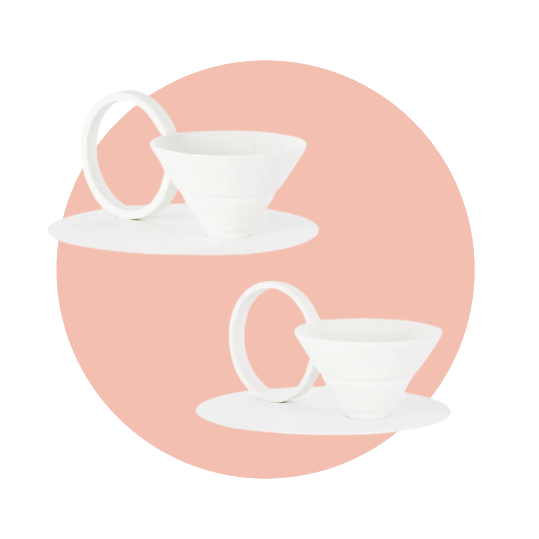 Two white teacups with triangular bowls, large circular bases and handles on a light pink circle graphic