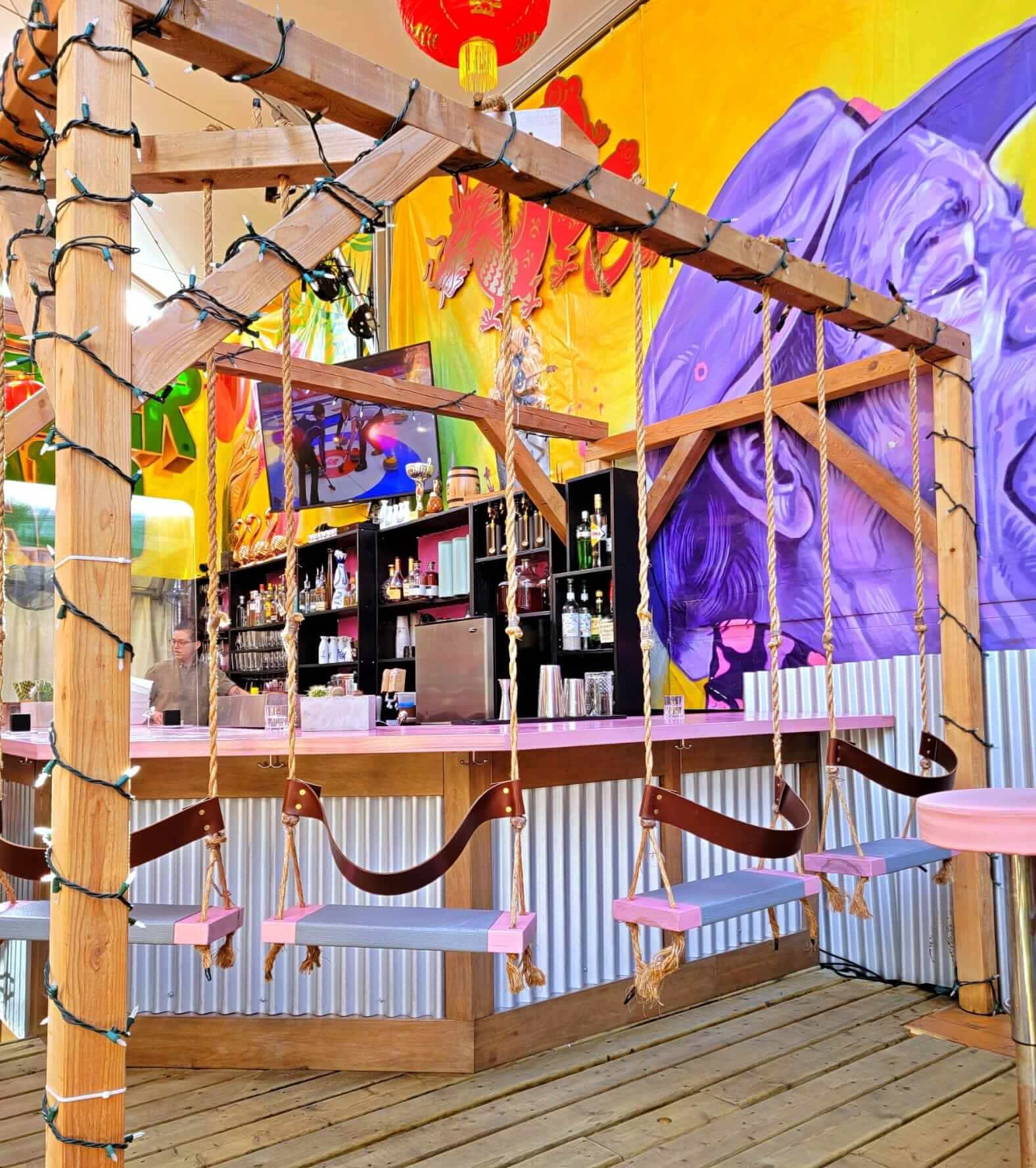 A bar with swings for chairs and a colourful mural