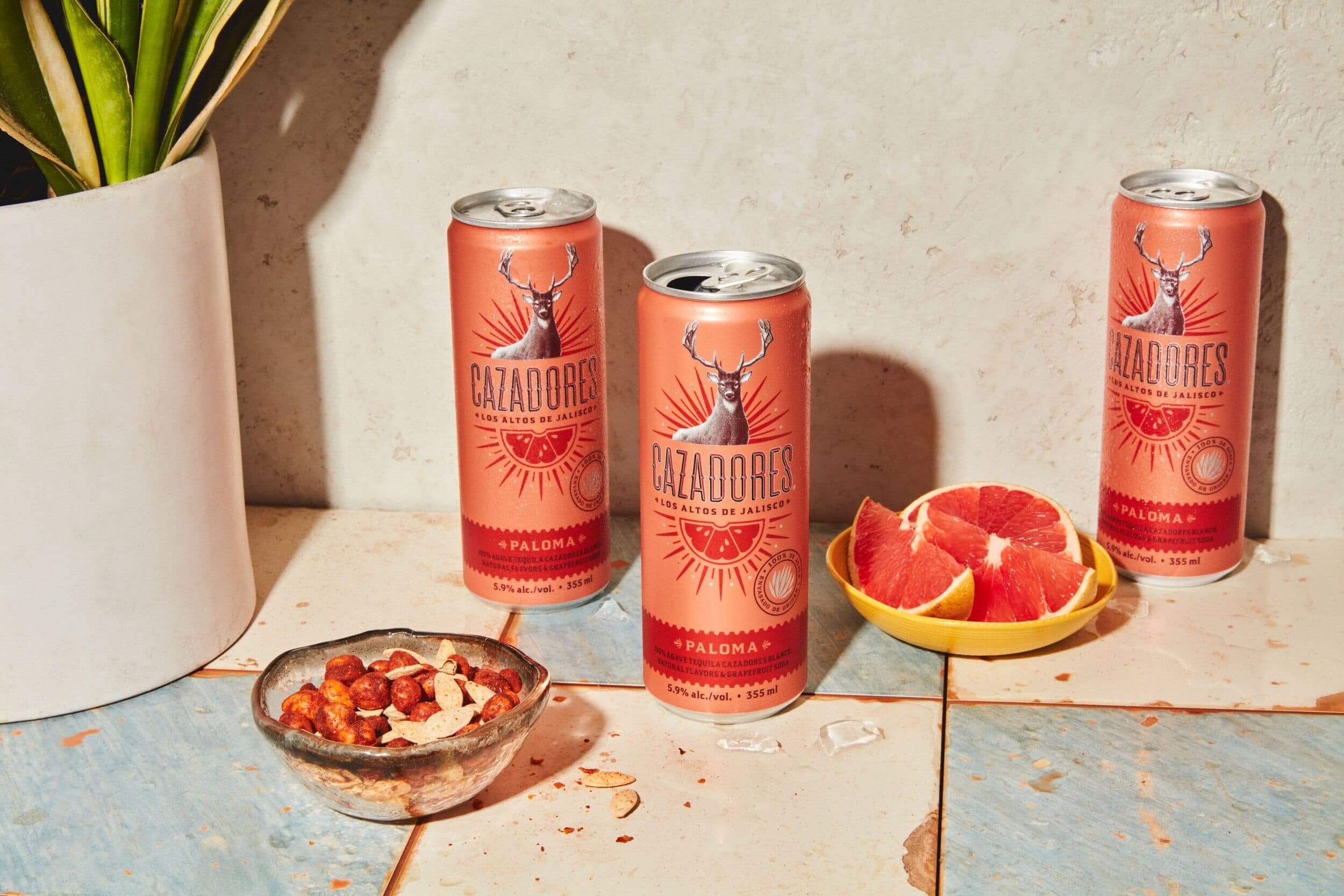 Two pink cans sitting on tiles with grapefruit pieces