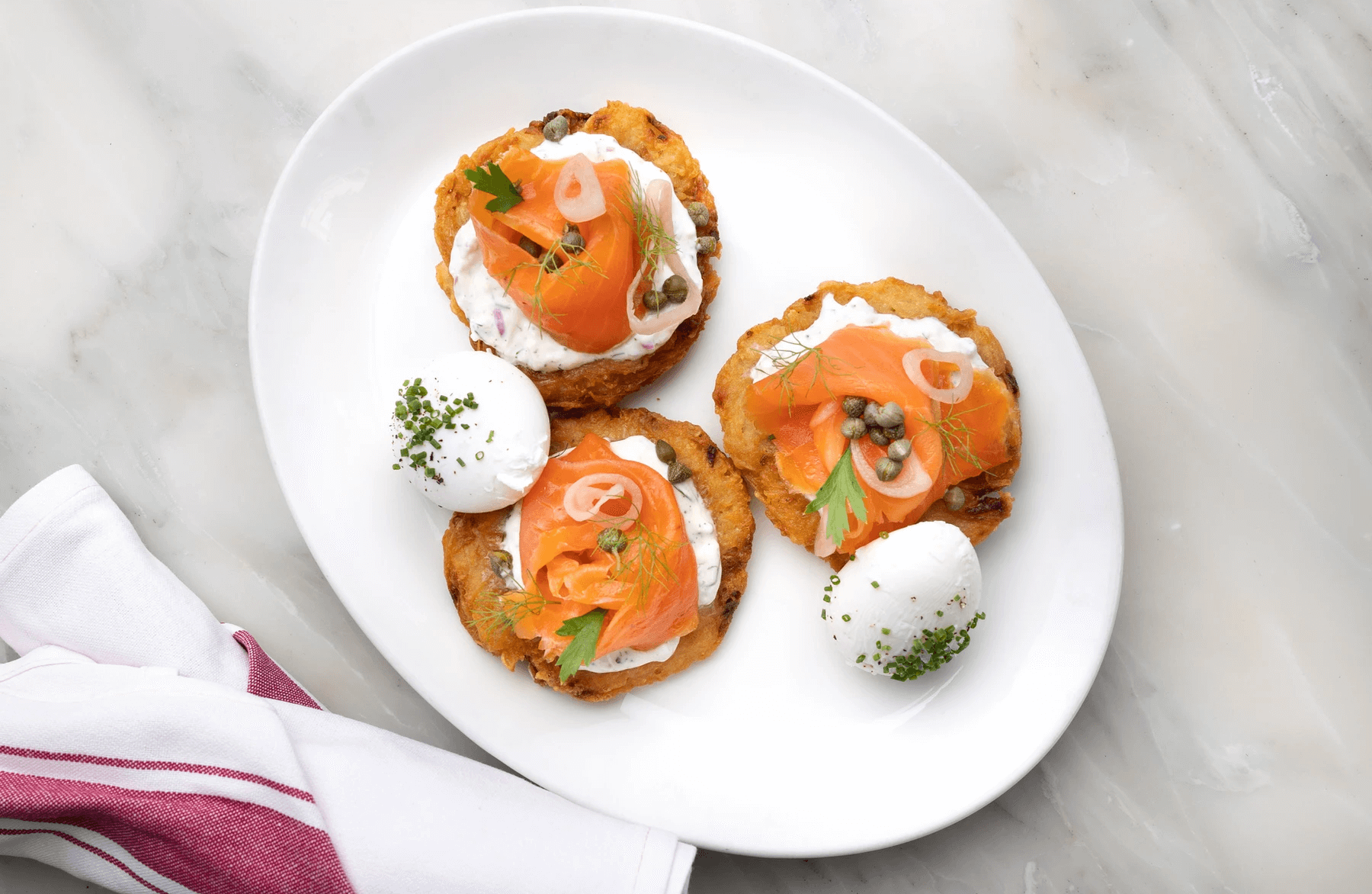 Potato cakes with smoked salmon and cheese on a white plate